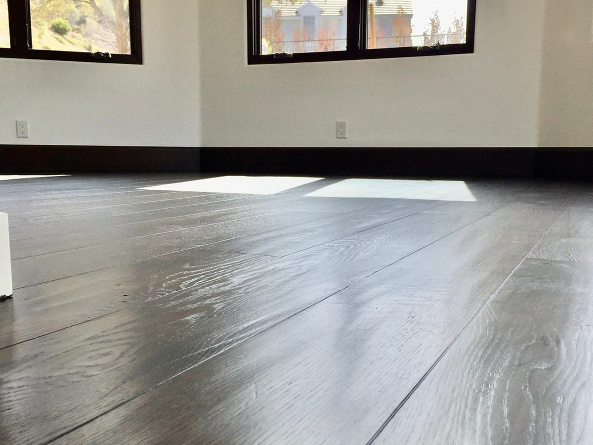 Completed Acacia Wood Floors project — close-up of gray-stained hardwood floor with rich grain character and glossy refinish