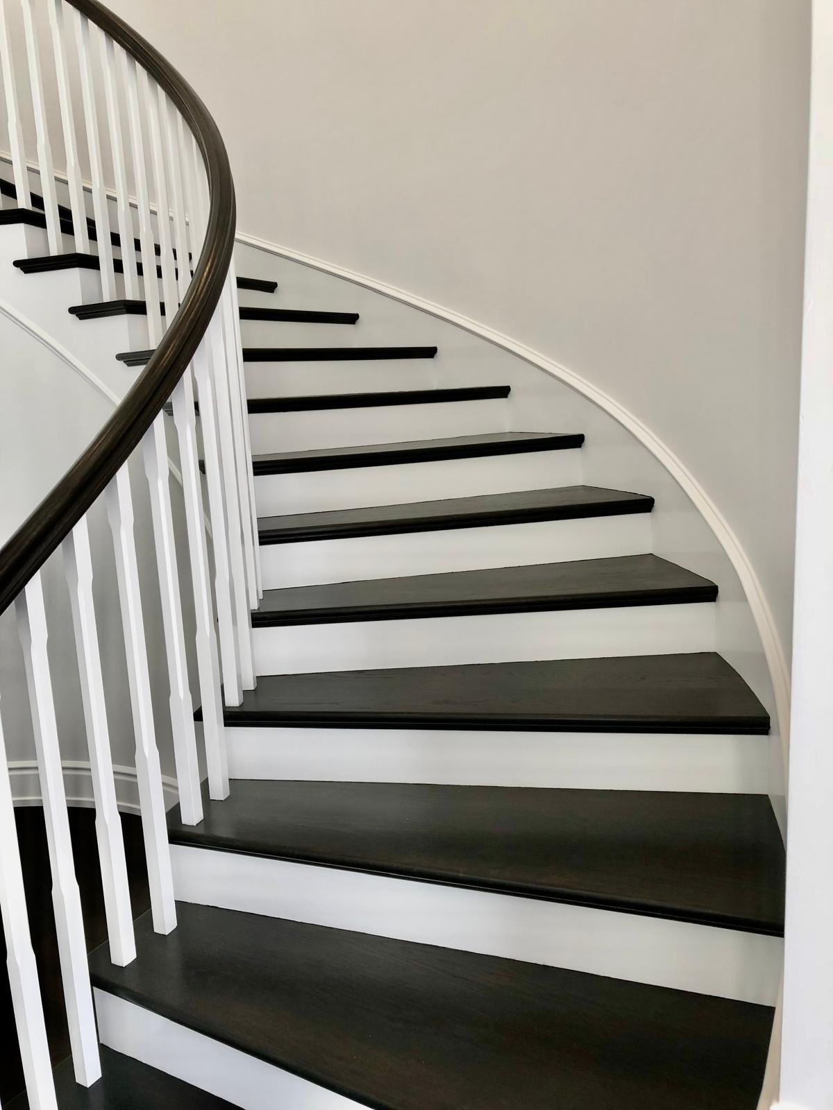 Completed Acacia Wood Floors project — curved staircase with espresso-stained treads, white risers, and white balusters