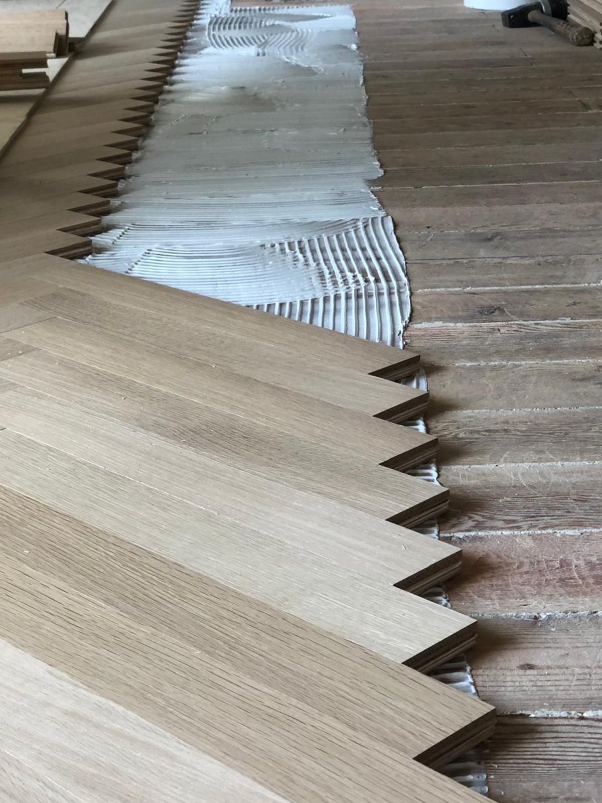 Acacia Wood Floors project in progress — new oak flooring installed next to old weathered plank, showing the contrast of a restoration or replacement