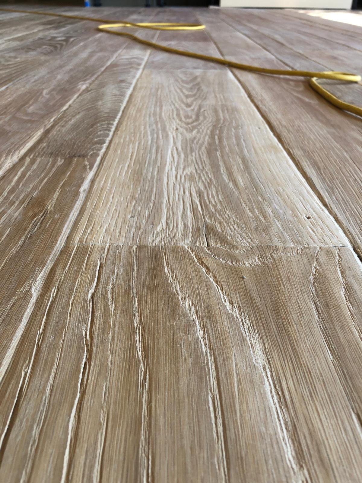 Acacia Wood Floors project — close-up of light gray wood plank flooring with natural grain texture during installation